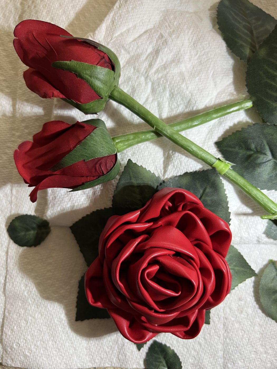 Handmade red satin ribbon rose on a leafed stem